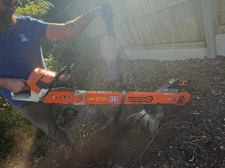 Andrew working the Terminator, a chainsaw-powered stump grinder, chips flying